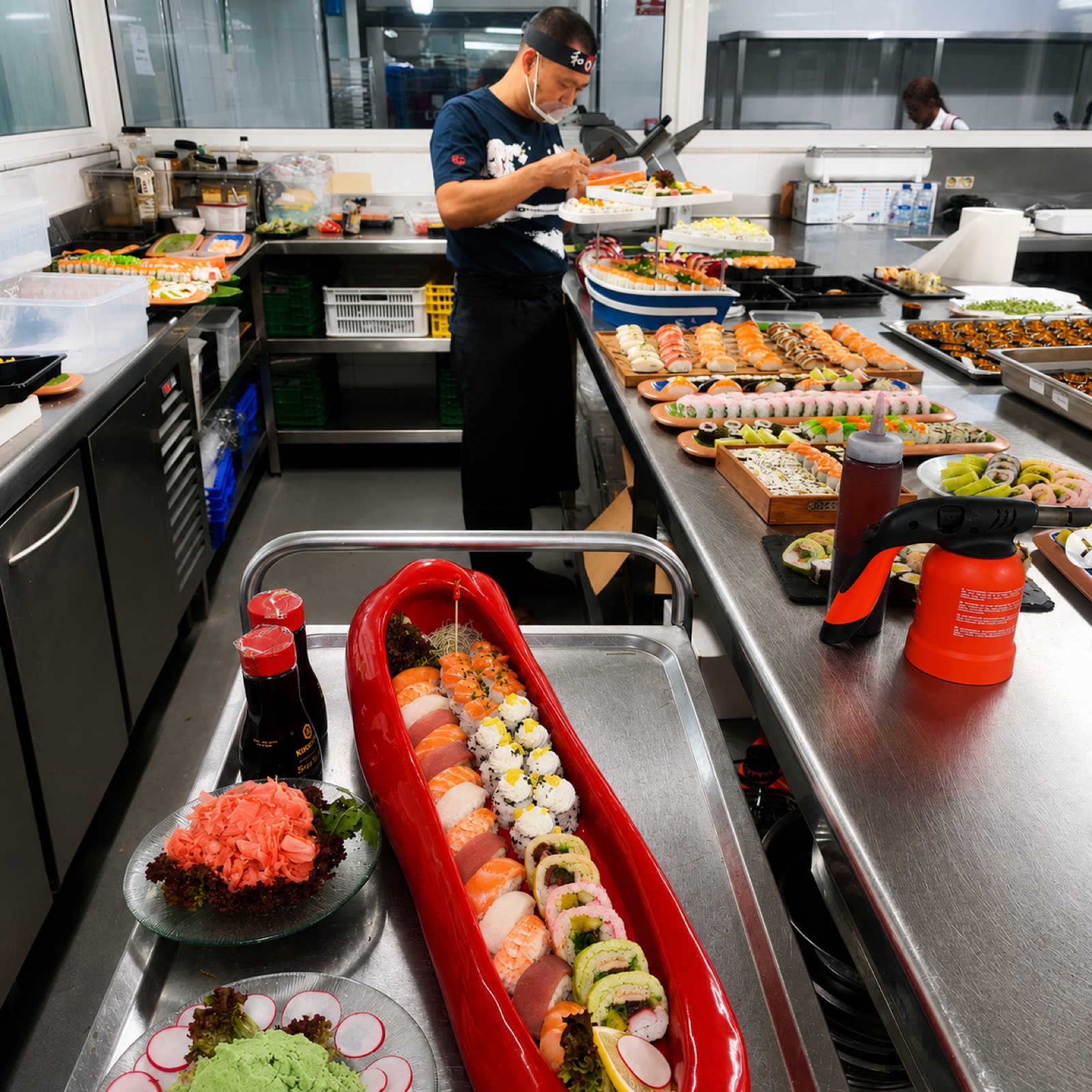 El señor Li preparando bandejas de sushi para un evento en la cocina profesional