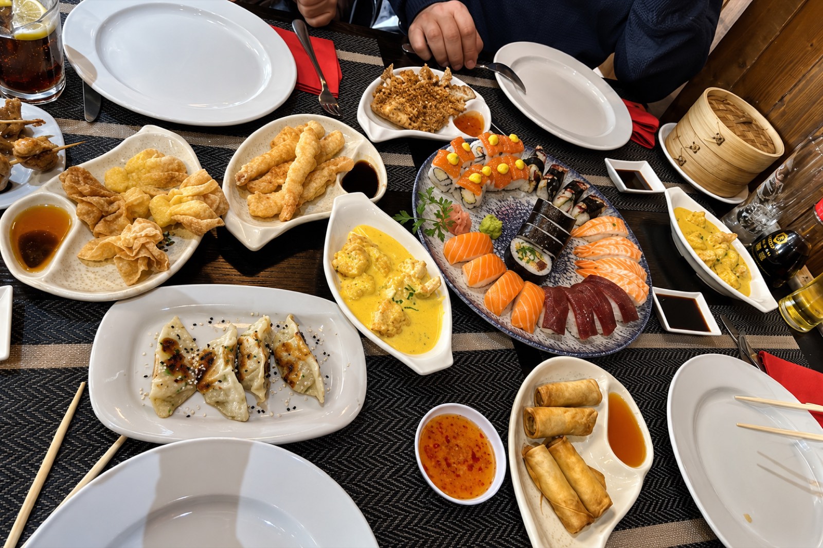 Mesa servida con gyoza, tempura, sushi y rollitos de primavera