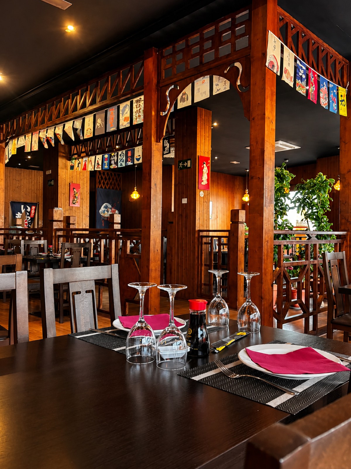 Comedor de Yamato Gandía con vigas de madera y banderines japoneses colgantes